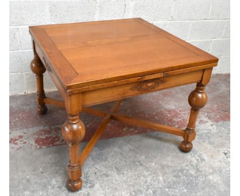 A 1930s golden oak extending dining table, the square top with two pullout leaves, on baluster and block legs and turned feet