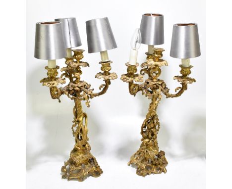 A pair of late 19th century French gilt brass Louis XV style four branch candelabra, converted for electricity, cast througho