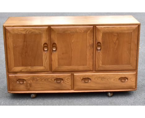 ERCOL; a light elm sideboard, the three panel doors above two base drawers, width 129cm, depth 43cm, height 75cm.