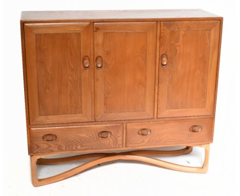 ERCOL; a rare elm and beech sideboard with three panel doors above two drawers, complete with internal drawers, raised on bee