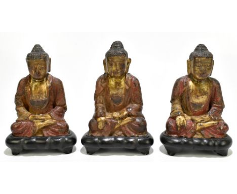 A set of three Chinese late 19th/20th century carved, painted and gilt seated figures, comprising Amitabha, Shakyamuni and on