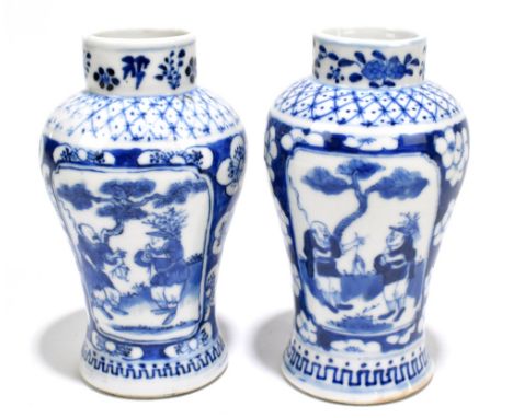 A pair of late 19th century Chinese Kangxi style blue and white vases, decorated with panels of fishermen within prunus flowe