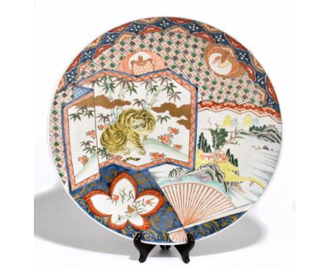 A late 19th century Japanese Imari wall charger of circular form, decorated with a seated tiger on folding screen beside land