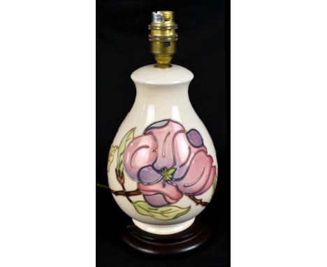 MOORCROFT; a baluster form table lamp decorated in 'Magnolia' pattern on an ivory ground, raised on a turned wooden plinth ba