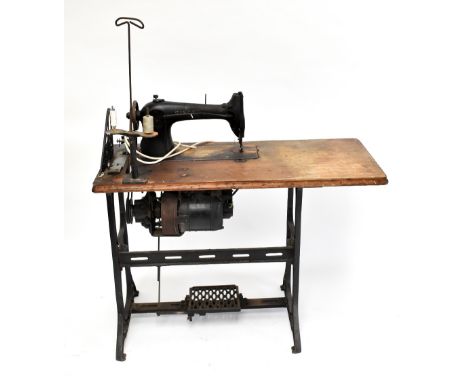 SINGER; an electric and treadle vintage sewing machine and integral stained pine and cast iron table frame, height of the tab