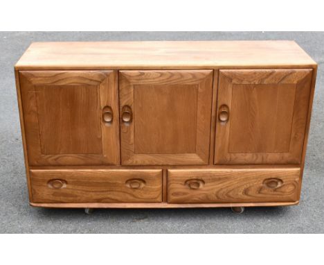 ERCOL; a light elm sideboard, with three panel doors above two base drawers, width 129cm, depth 43cm, height 75.5cm.