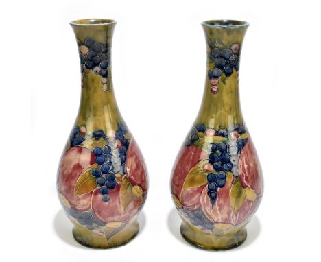 WILLIAM MOORCROFT; a large pair of baluster vases decorated in the ‘Pomegranate’ pattern on an ochre ground, green signature 
