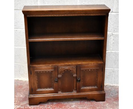 An oak open bookcase, with two shelves above two carved panelled cupboard doors, on bracket feet, height 103cm, width 84cm, d