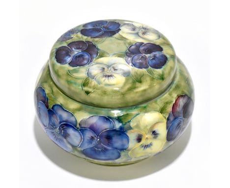 WILLIAM MOORCROFT; a circular powder bowl with screw cover decorated in the ‘Pansy’ pattern on a green ground, green signatur