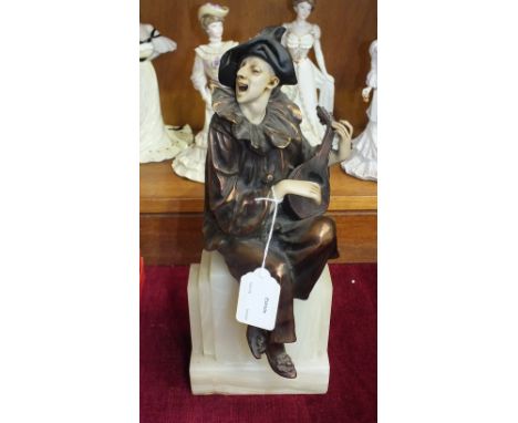 An Art-Deco-style bronzed metal and faux ivory figure of a clown seated on a pedestal and playing a lute, on alabaster base.