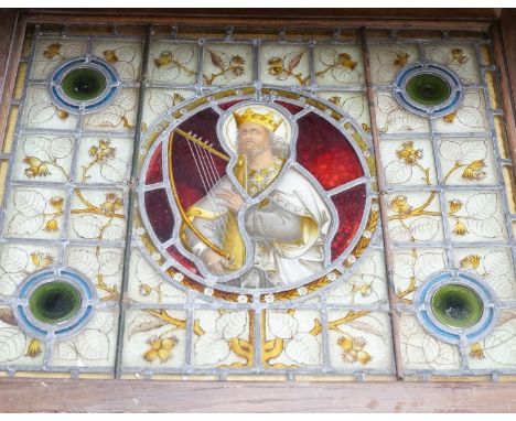 A framed Victorian stained glass panel depicting King David playing the harp, 58x70cm including frame