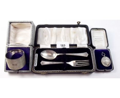 A silver Christening spoon and fork set, a silver Rhodesian medal and a silver napkin ring - all cased