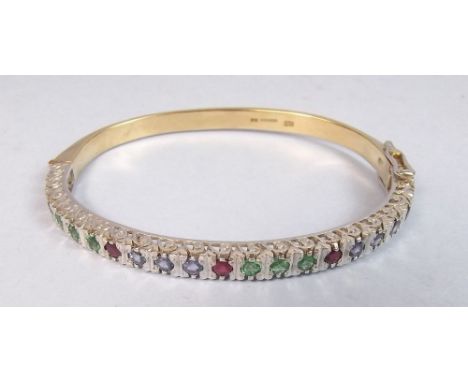 A 9 carat yellow and white gold hinged bangle set rubies, emeralds and ceylon sapphires - 17g