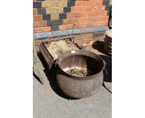 A metal cauldron together with a square grate converted to planter