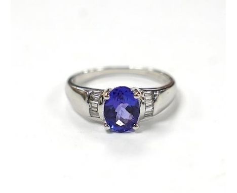 A modern 18ct gold and single stone oval cut tanzanite set ring, with baguette cut diamond cluster set shoulders, with accomp