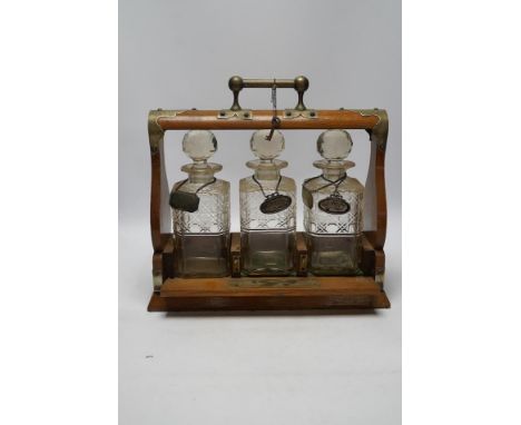 A Victorian oak three decanter tantalus with four spirit labels, and key, 37cm wide. Condition -fair Plated mounts all worn; 