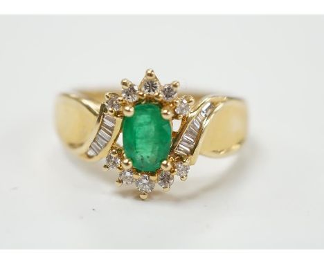 A modern 14k, emerald and diamond cluster set ring, with baguette cut diamond set shoulders, size Q, gross weight 4.9 grams. 
