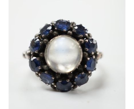 An Arts &amp; Crafts white metal, moonstone and sapphire set circular cluster ring, in the manner of Sibyl Dunlop, size M. Co