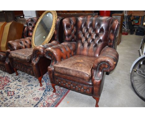 A pair of Gentleman's club style button back leather wing back armchairs, worn patina, possibly replacement legs