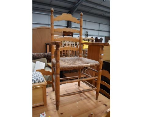 A set of four (three plus one carver) light stained ladder back chairs having rush seats