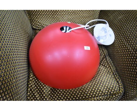A large ceiling light fitting with red half sphere shade, in the industrial style