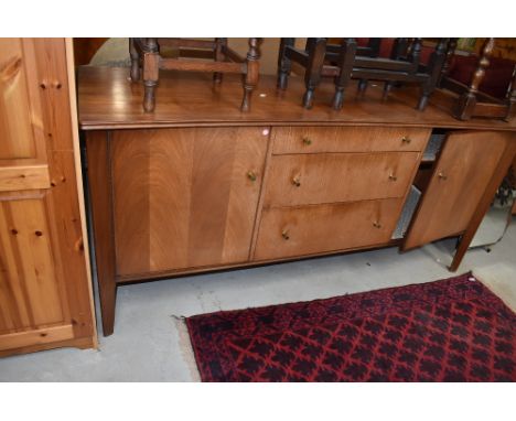 A vintage sapele sideboard of stylised form, three central graduated drawers with brass handles, flanked by cupboards, concav