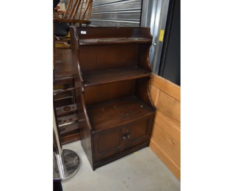 A dark stained Ercol shelf unit with cupboard under, width approx. 61cm