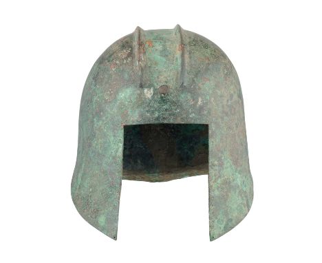 A GREEK BRONZE HELMET OF ILLYRIAN TYPE, 6TH-5TH CENTURY B.C.  ‡ formed in one piece with a rounded crown decorated to either 