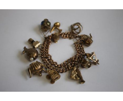 A 9CT GOLD AND YELLOW METAL CHARM BRACELET, charms include a railway lamp, kettle and fish etc.