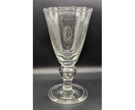 An oversized drinking glass, the round funnel bowl with solid base above a teared shoulder knop and folded foot, h.28.5cmSome
