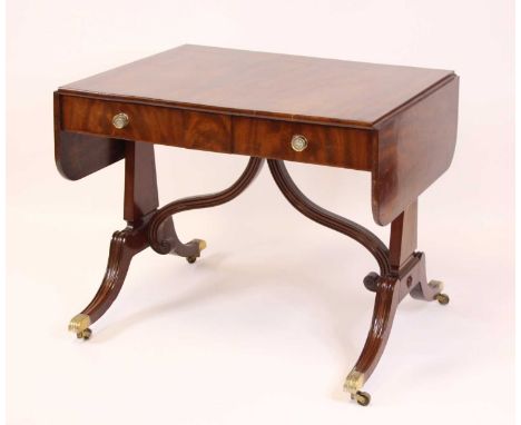 A Regency mahogany pedestal sofa table, having fall leaves with rounded corners, twin frieze drawers with pressed brass knobs