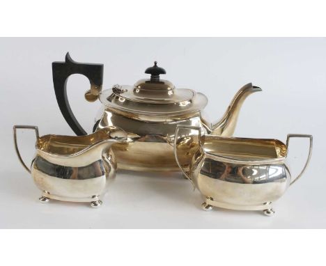 A George V silver three-piece tea service, comprising teapot with ebonised handle and finial, twin handled sugar bowl, and cr