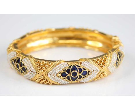 A yellow metal Etruscan style circular hinged hollow bangle, having six kite shaped sections of blue enamel inlay and twelve 