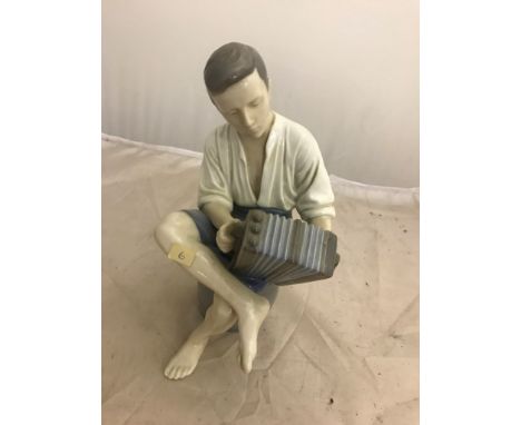 A B&G figure of a boy playing an accordion sitting on a barrel