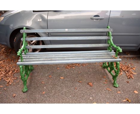 A garden bench, having wooden slats with green painted cast iron serpent and dog bench ends, 142cm wide. 