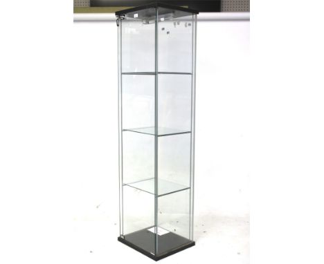 A contemporary glass shop display cabinet. Containing three shelves behind a locked door (key present), electric light fitted