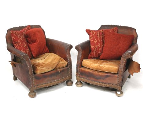 A pair of vintage brown leather armchairs. With a studded frame, raised on turned oak supports, upholstered with two orange v