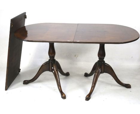 A regency style mahogany twin pedestal dining table. With curved ends and an additional leaf, the pedestals with a turned cen