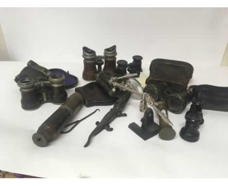 A collection of Opera glasses a telescope a magnifying glass on an adjustable stand and other oddments.