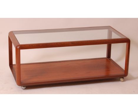 A 1960s Danish teak two tier coffee table, having a clear glass inset top over platform undertier to roller castors, h.46cm, 