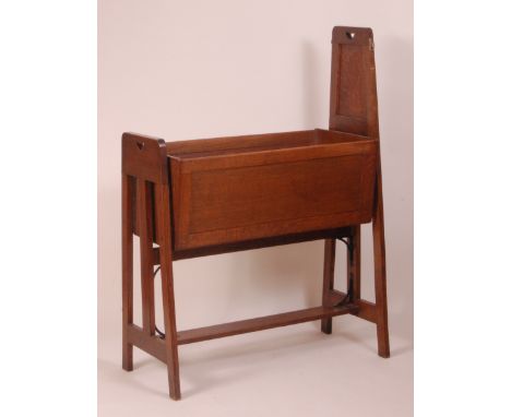An Arts & Crafts panelled oak baby's rocking crib, each end support having pierced heart shaped cut-outs and of 'A' form, wit