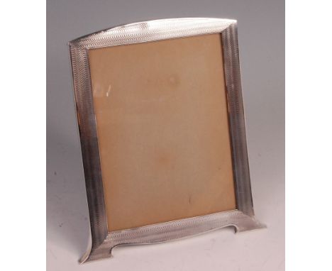 An Art Deco silver photograph frame, having stylised engine turned border, on outswept supports, housed in an oak backboard a