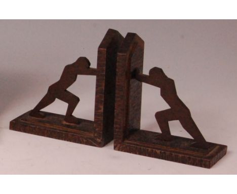 A pair of Art Deco lacquered steel book-ends, each in the form of standing profile geometric stylised males pushing against a