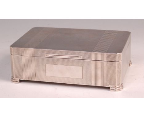 An Art Deco style silver table cigarette box, having a hinged cover with reeded banding and all-over engine turned decoration