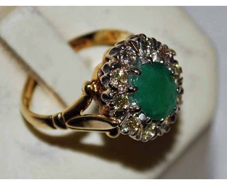 An 18ct Gold Diamond and Emerald style Ring, central oval stone surrounded by ten small diamonds, set in white gold, London 1