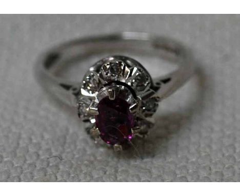 An 18ct white gold Ruby and Diamond Cluster Ring, central oval ruby surrounded by eight small stones, ring size O, 5.3g, Shef