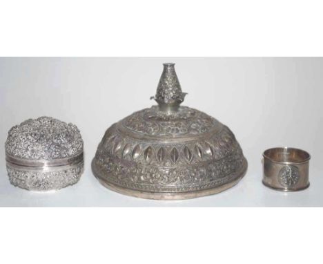 Three eastern silver wares comprising of a Southeast Asian repousse silver lidded box 7.8cm diameter, a Burmese silver lid (1