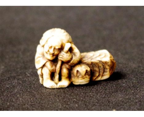 Japanese carved ivory netsuke Seated Man on a Wall, signed to base, (length 4cm approx). NOTE: Export of this item is not per