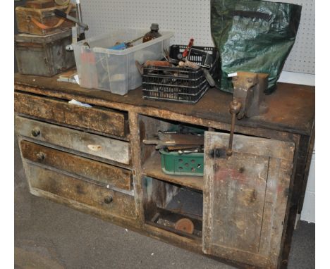 A large wood work bench set with a vice and a large selection of tools