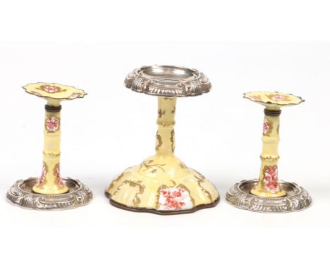 A garniture of three 18th century Bilston enamel taper sticks. Having pewter mounts, yellow ground, gilded with rococo scroll